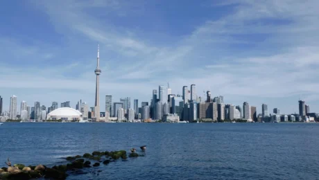 akcni-letenky-praha-toronto-9440kc-uvodni Pohled na Toronto skyline z jezerního břehu Lake Ontario v podzimním dni — běžní cestovatelé pozorují město přes vodu